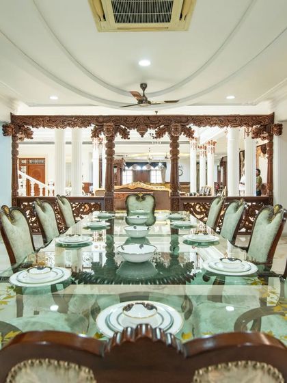 A view across the long dining table, looking towards the intricately carved wooden screen that separates it from the main hall.