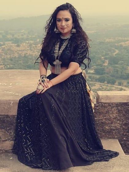 The full look for the singer in 'Jogan'. I used a shimmering black lehenga and choli set, accessorized with heavy, traditional silver pieces to create a powerful silhouette against the rustic, historic backdrop.