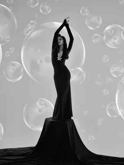A full-length, statuesque pose from the bubble series. The model's arms are raised in a graceful, dance-like position, making her look like a living sculpture.