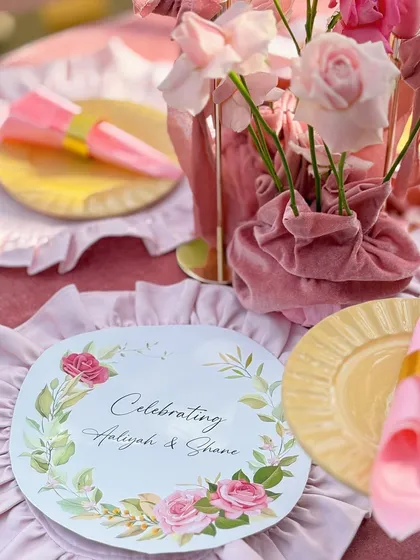 A personalized placemat celebrating the bride and groom, surrounded by pink napkins and floral details.