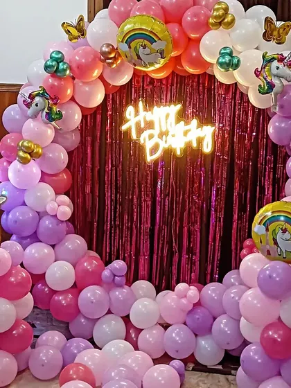 A very popular unicorn theme decoration for a first birthday. This features a full circular balloon arch in pink, purple, and white, with a bright pink shimmer curtain in the middle. I added a 'Happy Birthday' neon sign for a modern touch.