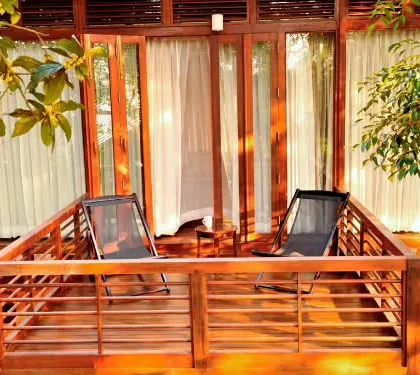 The private wooden balcony of a nature lodge in Coorg. This is the perfect spot to enjoy your morning coffee while listening to the sounds of the forest and watching the mist roll over the hills.