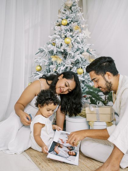 A family looking at their photo album by the Christmas tree. A beautiful moment of reflection and joy.
