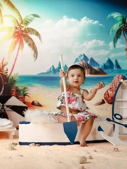 A vibrant beach-themed studio shoot for a first birthday, with a little girl ready to play in the sand.