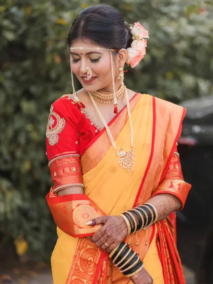 The bride looking down with a gentle smile, a simple and elegant pose that highlights the details of her embroidered blouse and saree.