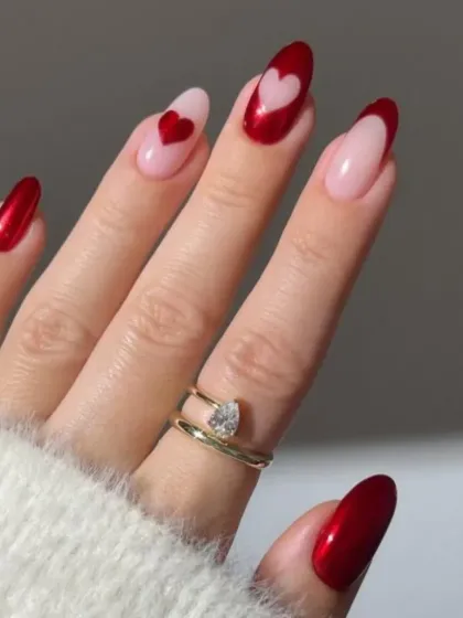 A romantic and modern design with red chrome, sheer pink, and heart-shaped cutouts and art on almond-shaped nails.