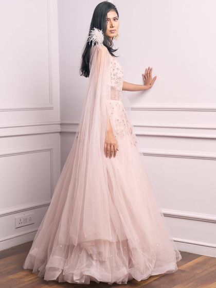 A side view of our pale pink princess gown, showing off the beautiful cape and feather details.