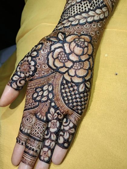 A close-up of a single palm showcasing a large, detailed rose as the centerpiece, surrounded by other floral and geometric patterns.