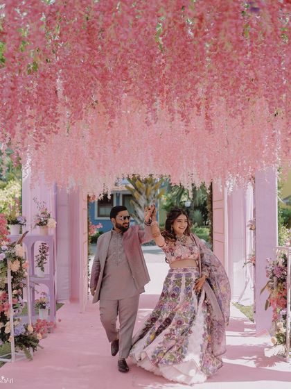 A couple makes their entrance through a stunning tunnel of pink flowers. This photo showcases the beautiful and immersive decor of their event.