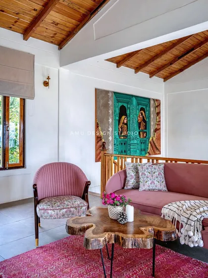 The upper-level lounge area, furnished with a pink sofa and a live-edge wooden coffee table, provides a perfect spot for relaxation.