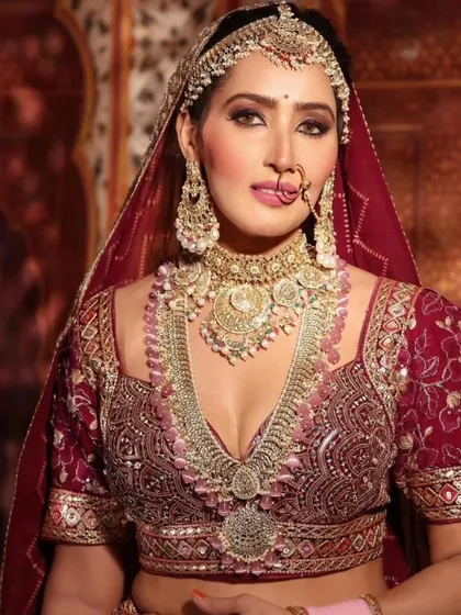 A close-up of a magnificent bridal look, featuring a deep V-neck blouse and a heavy, layered choker and necklace set with pink bead detailing.