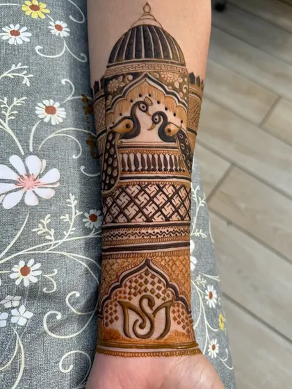 An elegant armband design featuring two peacocks under a dome, with swastika patterns and a custom initial monogram.