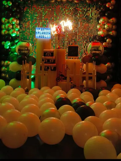 A low-light shot showing how green spotlights can create a unique mood. The sequin wall and metallic balloons catch the light for a dazzling effect.