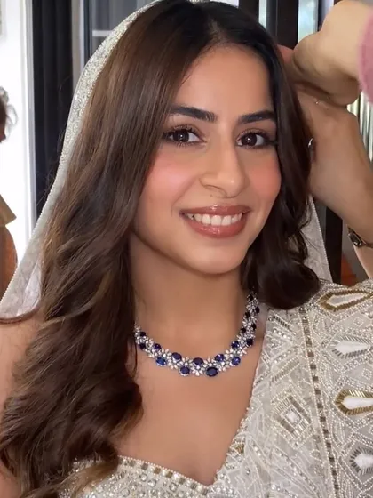 A close-up of our beautiful bride Rian, glowing in her custom sapphire and diamond necklace set against an elegant white ensemble.