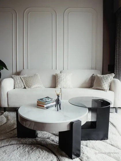 A detail shot of the living room at Sai World Empire, focusing on the elegant white sofa and modern coffee table. The wall molding adds a classic touch to the contemporary design.