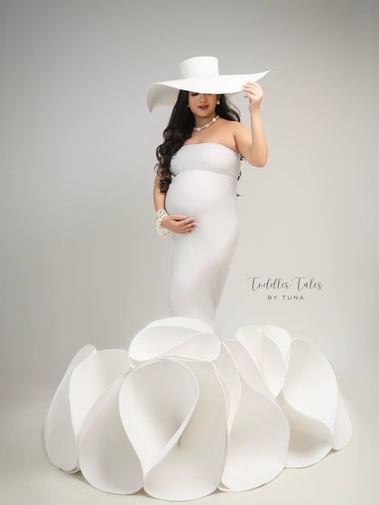 A slightly different angle of the iconic white flower gown, showcasing its unique design and the mother's serene expression. This is a perfect example of a concept maternity session.