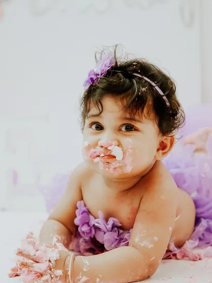 A sweet, frosting-covered face peeking at the camera. Even the quiet moments during a cake smash are incredibly precious.