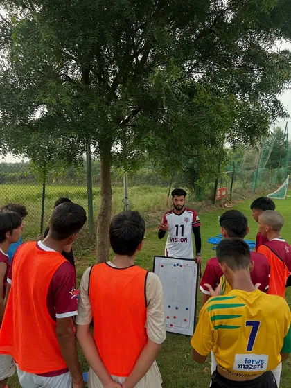 A coach uses a whiteboard to illustrate a tactical setup to his players. We believe that understanding strategy is just as important as physical skill.