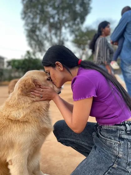 A visitor gives a gentle kiss to the top of a Golden Retriever's head, a perfect picture of love.
