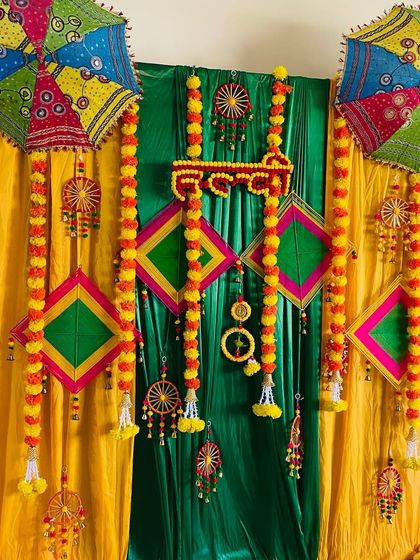 Another angle of the colorful Haldi backdrop with traditional umbrellas and kites.