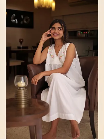 A candid-style shot of a smiling model in a white loungewear set, seated in a warmly lit room. This image creates a cozy and relatable atmosphere for the brand.