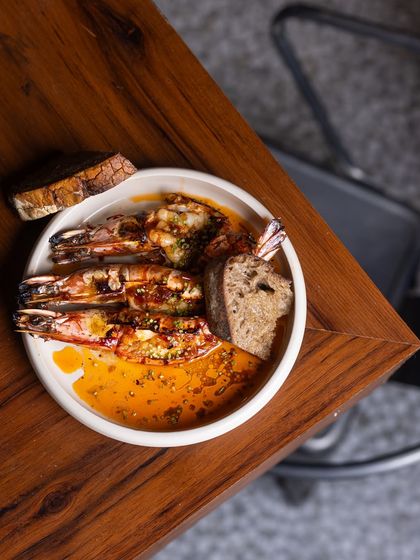 When the flames kiss the prawns and the butter starts to sizzle, magic happens. My King Prawns are slow-cooked with garlic butter and a hint of fermented chili, served with warm sourdough for dipping.