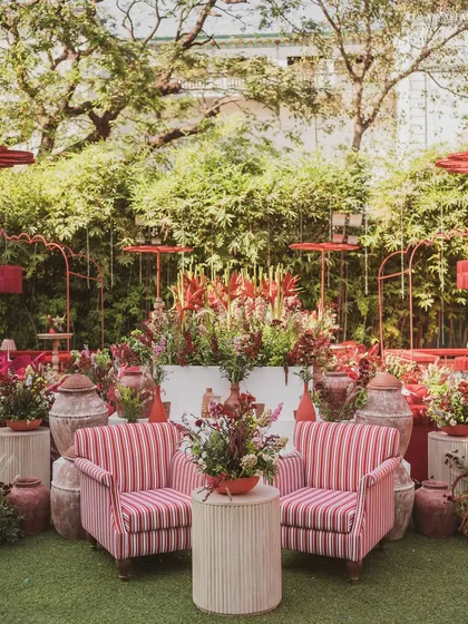 A cozy seating arrangement with striped armchairs, surrounded by lush florals and rustic terracotta pots.