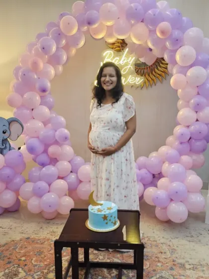 The beautiful mom-to-be posing in front of her pastel-themed baby shower decor. The purple and pink balloon arch creates a perfect frame for photos.