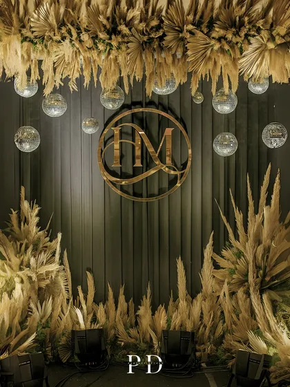 The photo booth backdrop with dramatic lighting. The interplay of shadows and light on the pampas grass and draped fabric adds depth and texture.