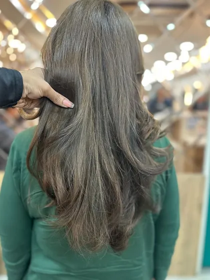 The stylist's hand gently brushing through the freshly colored hair, demonstrating its softness and healthy condition.