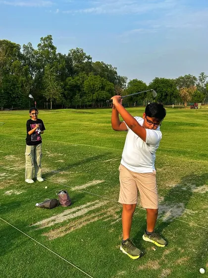 A young golfer executes a perfect follow-through, learning the game alongside a friend.