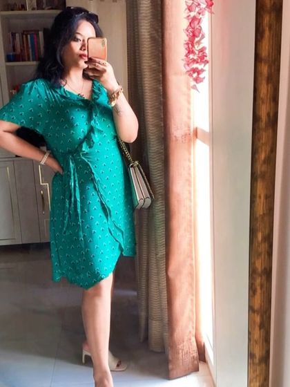 A mirror selfie of the green wrap dress, showing its flattering fit.