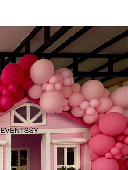 A close-up of the balloon garland cascading over the roof of the pink playhouse.