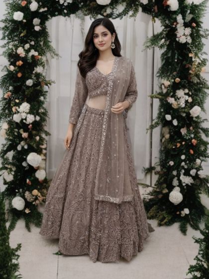 A full-length view of the taupe-brown lehenga, showcasing its graceful silhouette and the sheer, sparkling dupatta.
