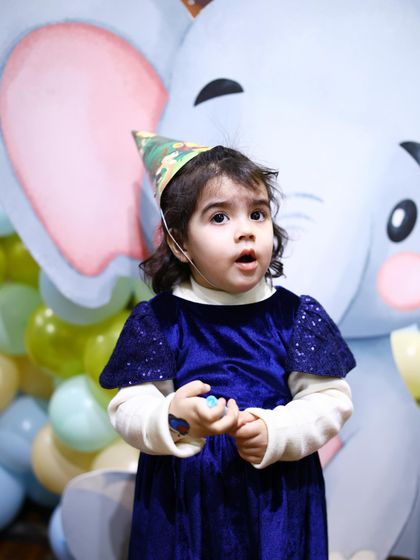 The birthday girl, wearing a cute safari hat, looks on with wonder at her jungle-themed party. We love seeing the children's reactions to our immersive decor.