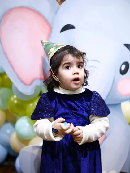 The birthday girl, wearing a cute safari hat, looks on with wonder at her jungle-themed party. We love seeing the children's reactions to our immersive decor.