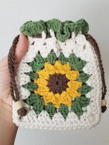 Our popular crochet sunflower pouch, designed with a classic granny square pattern. This drawstring bag is perfect for storing small treasures like coins, jewelry, or earphones, and is handmade with soft, washable yarn.