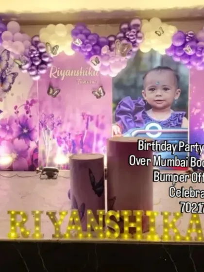 A personalized butterfly theme in purple and white. This large stage setup includes a custom backdrop with the birthday girl's photo, balloon arches, and marquee letters.