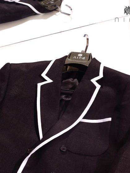 Our modern black double-breasted blazer features a striking white piped edge. This sharp detail elevates the classic design, making it perfect for high-impact occasions.