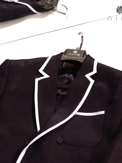 Our modern black double-breasted blazer features a striking white piped edge. This sharp detail elevates the classic design, making it perfect for high-impact occasions.