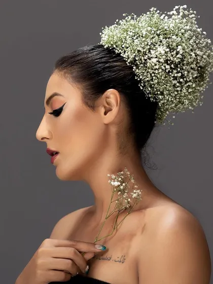 A side profile from the same floral beauty shoot, highlighting the model's elegant neckline and tattoo.