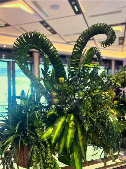 A garden of sweetness. This dessert table features whimsical, dinosaur-like sculptures made of curled palm fronds, surrounded by an abundance of sweets and treats.