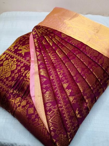 A rich wine-colored saree with intricate gold weaving. The pleats are done with precision to highlight the beautiful craftsmanship of the saree.