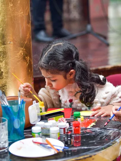 A young artist completely absorbed in her painting. I provide all the supplies for kids to create their masterpieces during brunch, offering a perfect blend of artistic fun and family dining.