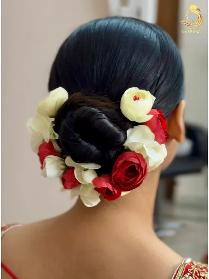 A clean, sleek bridal bun adorned with a mix of red and white flowers for a classic look.