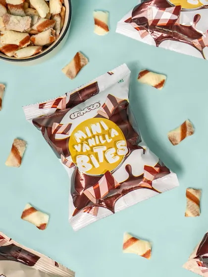 A scattered arrangement of mini vanilla bites and their packaging. This casual, top-down flat lay feels energetic and is great for website backgrounds or social media.