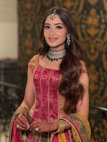 A portrait of the bride, her hair styled in simple, glossy waves that complement her glowing makeup and stunning jewellery.