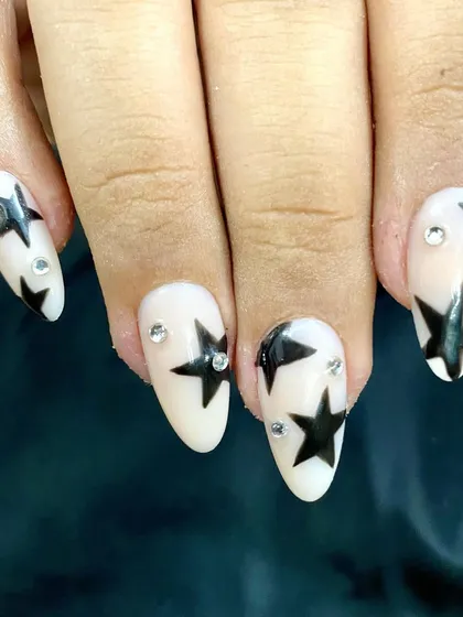 A close-up shot showing the clean lines of the hand-painted stars and the placement of the crystal accents. These stick-on nails are completely reusable and made to fit you.