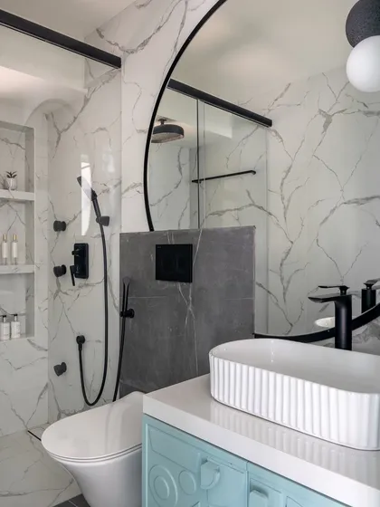 Another view of the kids' bathroom, showing the walk-in shower with its marble-patterned tiles and black fixtures. The space is modern, clean, and designed to grow with the child.