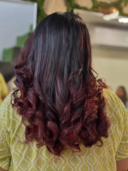This is a great example of a red ombre effect on dark hair. The color is concentrated at the ends and styled in beautiful curls to highlight the seamless blend from dark to vibrant red.